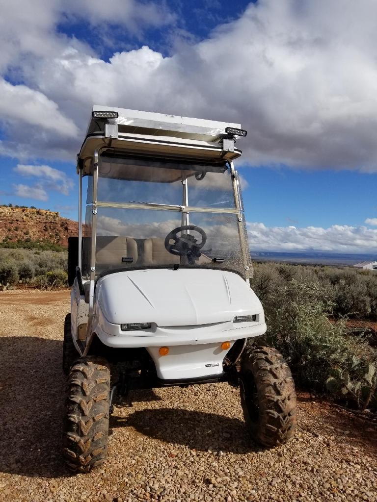 Front of a white lifted golf cart with light bar