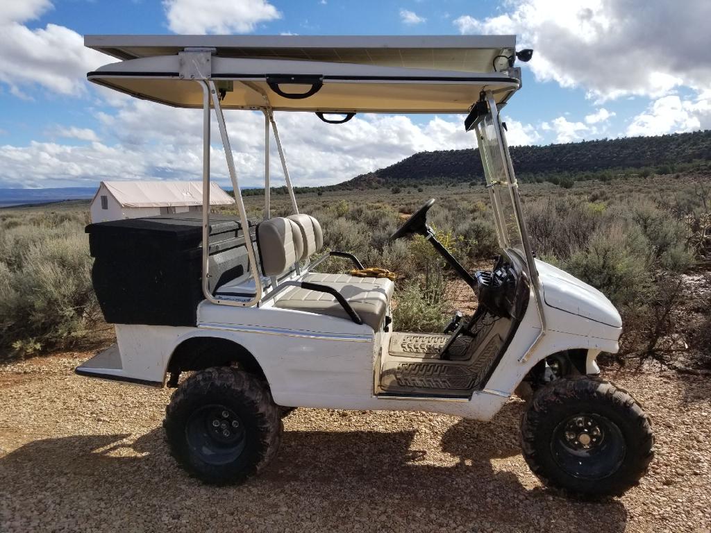 White off-road golf cart with solar roof and cargo box